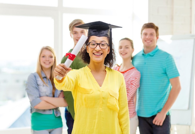 onderwijs en mensenconcept - glimlachende vrouwelijke student met diploma en hoek-pet en vrienden op de rug