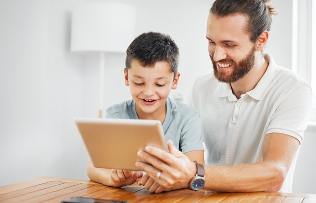 Onderwijs en ontwikkeling leren met een vader en zoon die thuis online studiemateriaal op een tablet doorbladeren Jonge jongen en zijn vader die huiswerk maken of studeren met internet als hulpmiddel