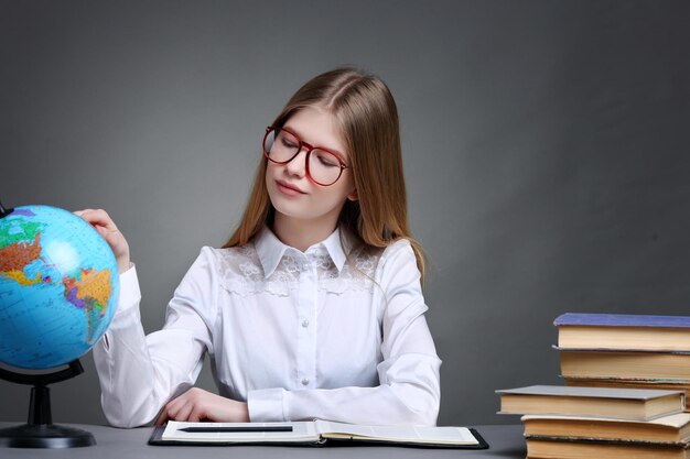 Onderwijs en schoolconcept klein studentenmeisje dat aardrijkskunde studeert met globe en boek