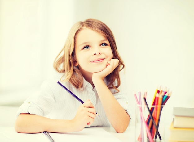 onderwijs en schoolconcept - kleine student meisje tekenen met potloden op school