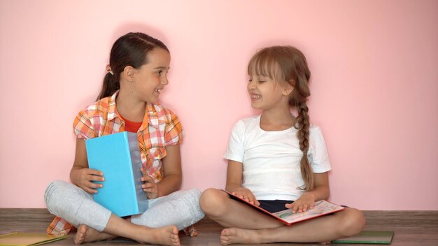 Onderwijs en schoolconcept - kleine studentenmeisjes die thuis een boek studeren en lezen