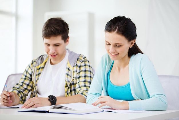 onderwijs en schoolconcept - twee glimlachende studenten met schoolboeken en boeken op school