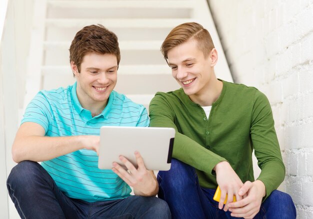 onderwijs en technologie concept - glimlachende mannelijke studenten met tablet pc-computer zittend op de trap