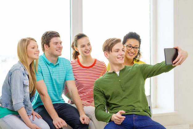 onderwijs en technologie concept - lachende studenten maken foto met tablet pc-computer op school