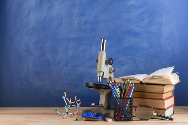 Onderwijs en wetenschappen concept boeken molecuulmodel en microscoop op het bureau op de achtergrond van het auditoriumbord