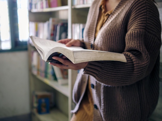 Foto onderwijs hand van een oudere vrouw die een boek vasthoudt in de bibliotheek