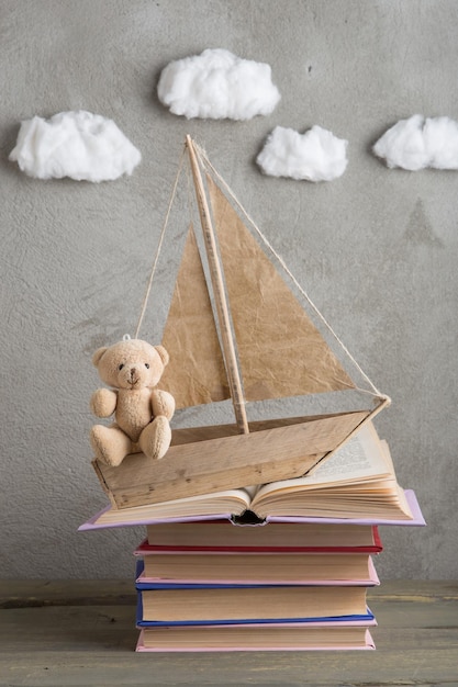 Onderwijs is een reisconcept speelgoedboot en boeken als een zee golven op de houten tafel inspiratie voor het schrijven van een sprookje