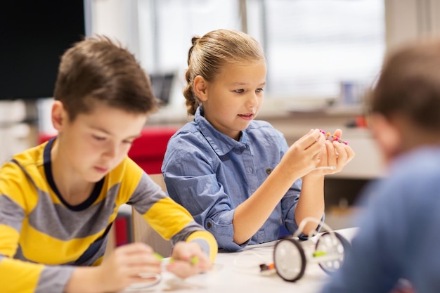 onderwijs, kinderen, technologie, wetenschap en mensenconcept - gelukkige kinderen die robots bouwen tijdens de robotica-schoolles