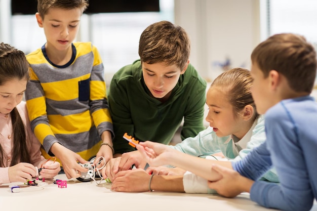 Foto onderwijs, kinderen, technologie, wetenschap en mensenconcept - groep gelukkige kinderen die robots bouwen tijdens robotica schoolles