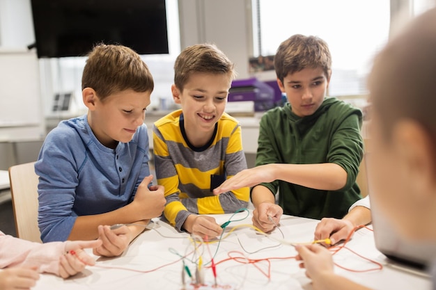 Foto onderwijs, kinderen, technologie, wetenschap en mensenconcept - groep gelukkige kinderen met uitvindingspakket bij robotica-schoolles