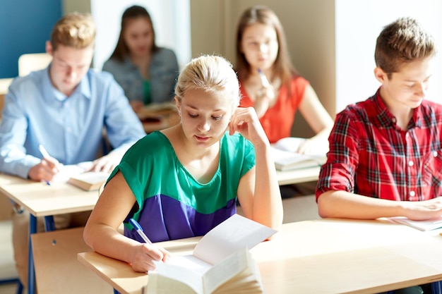 Foto onderwijs, leren en mensenconcept - groep studenten met boeken die schooltest schrijven