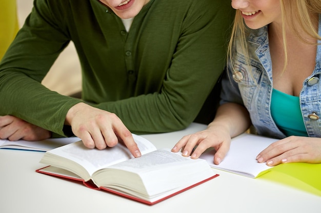 Foto onderwijs, mensen en schoolconcept - close-up van gelukkige studenten die leerboek of boek lezen op school