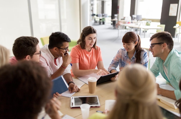 onderwijs, middelbare school, mensen en technologieconcept - groep internationale studenten die aan tafel zitten met tablet-pc's, boeken en notitieboekjes aan de universiteit