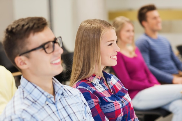 onderwijs, middelbare school, teamwork en mensenconcept - groep lachende studenten die in de collegezaal zitten