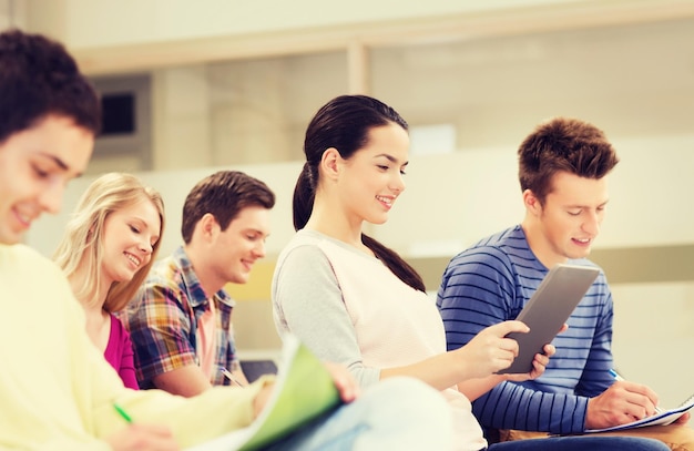 onderwijs, middelbare school, teamwork en mensenconcept - groep lachende studenten met tablet pc-computer en notebooks die in de collegezaal zitten