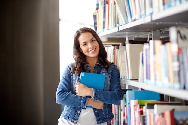 Onderwijs, middelbare school, universiteit, leren en mensen concept - glimlachend studentenmeisje leesboek bij bibliotheek