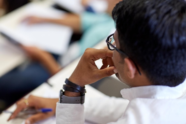 onderwijs, middelbare school, universiteit, leren en mensenconcept - close-up van de Indiase student tijdens de lezing