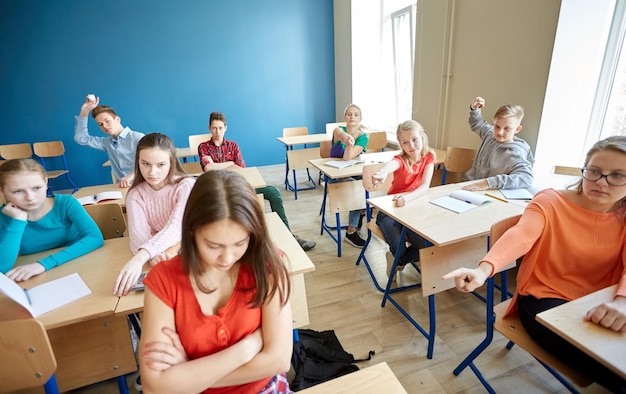 Foto onderwijs, pesten, conflicten, problemen en mensenconcept - studenten roddelen achter klasgenoot op school