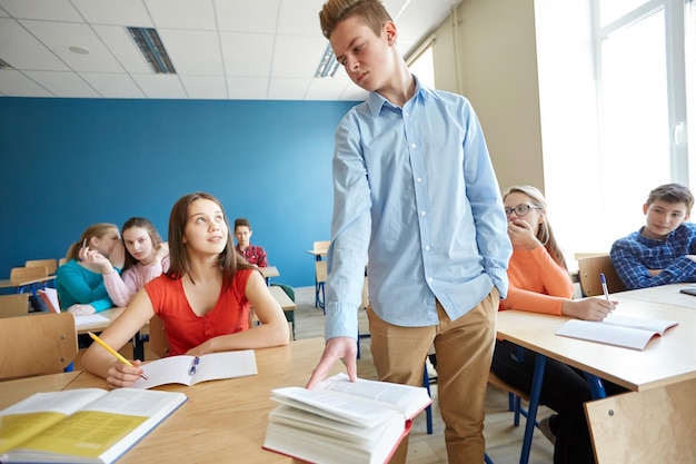 onderwijs, pesten, conflicten, sociale relaties en mensenconcept - studentenjongen die zich op school onvriendelijk gedraagt tegenover meisjes