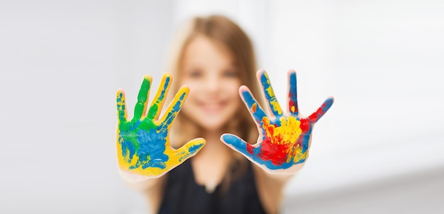 onderwijs, school, kunst en schildersconcept - klein studentenmeisje dat geschilderde handen toont