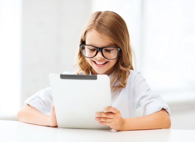 onderwijs, school, technologie en internet concept - klein studentenmeisje in zwarte bril met tablet pc-computer op school