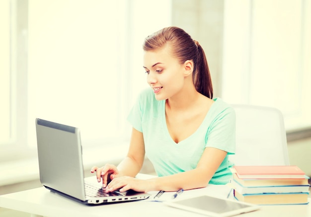 Onderwijs, technologie en internet concept - lachend student meisje met laptop