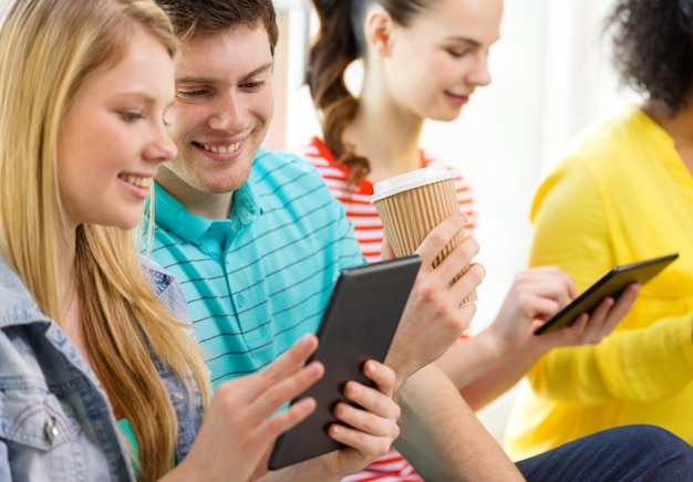 Foto onderwijs, technologie en internet concept - lachende studenten kijken naar tablet pc-computer op school