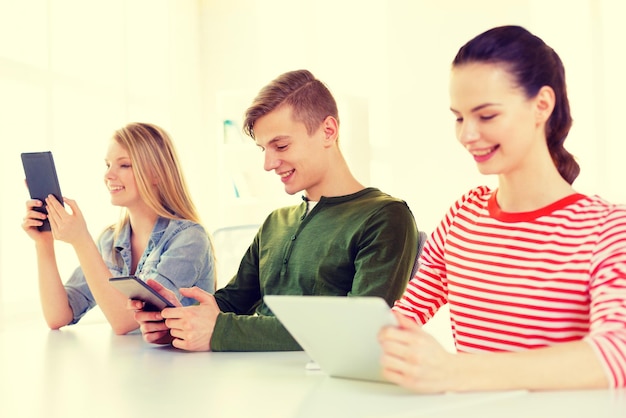 onderwijs, technologie en internet concept - lachende studenten kijken naar tablet pc-computer op school