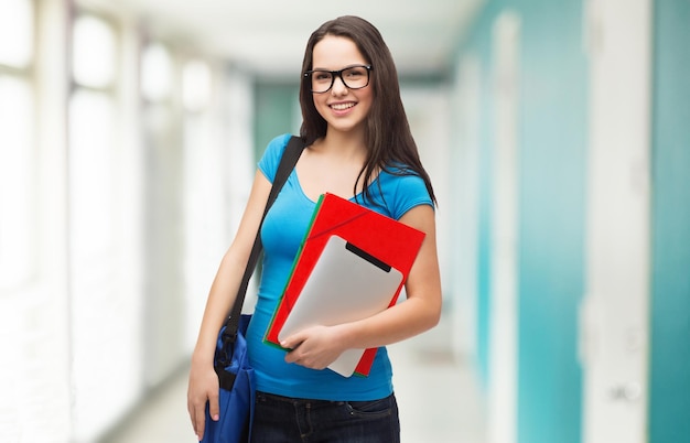 onderwijs, technologie en mensen concept - lachende student met zwarte bril met tas, mappen en tablet pc-computer staan