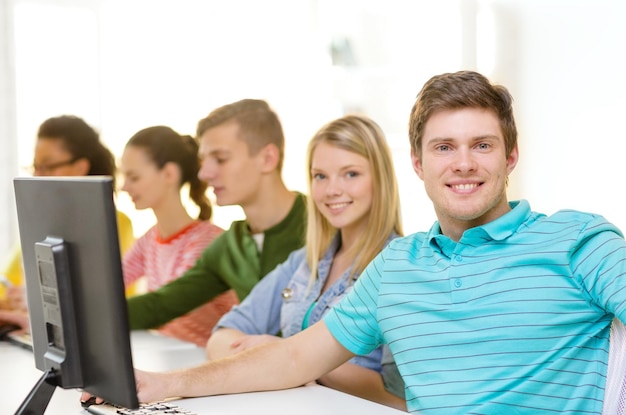 onderwijs, technologie en schoolconcept - glimlachende mannelijke student met klasgenoten in computerklasse