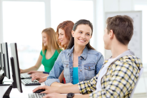 onderwijs, technologie en schoolconcept - lachende studenten in de computerklas op school die discussie hebben