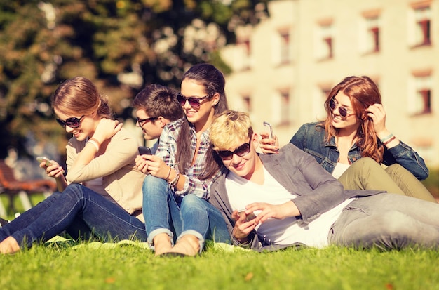 onderwijs, technologie, internet, zomervakantie, sociale netwerken en tienerconcept - groep tieners met smartphones