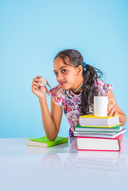 Onderwijs thuis concept - Schattig klein Indiaas of Aziatisch meisje dat thuis studeert met stapel boeken, educatieve wereldbol enz. Selectieve focus