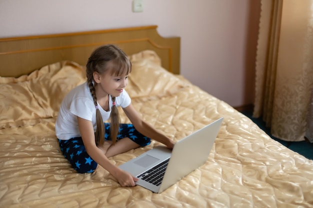 Onderwijs, vrije tijd, technologie en internetconcept - klein studentenmeisje met laptop thuis