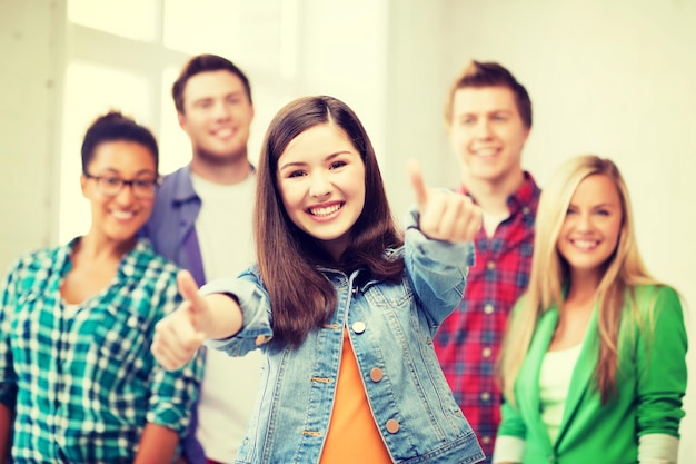 onderwijsconcept - gelukkig team van studenten die duimen opdagen op school