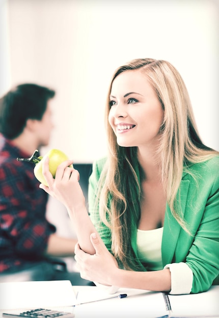 onderwijsconcept - glimlachend studentenmeisje met groene appel op universiteit