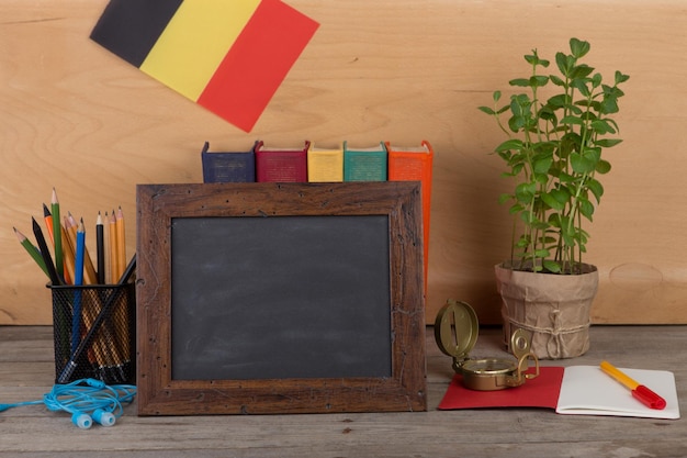 Onderwijsconcept - leeg bord, vlag van België, boeken, kanselarij op tafel en houten achtergrond