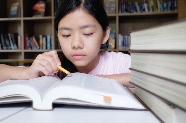 Onderwijsconcept. meisje lezen en schrijven in de bibliotheek van school.