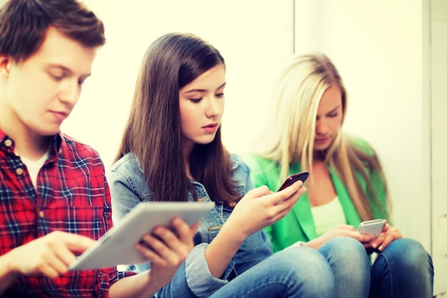 onderwijsconcept - studenten die op school naar telefoons en tablet-pc kijken