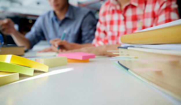 Foto onderwijsconcept. studenten studeren en brainstormen campus concept. close-up van studenten bespreken hun onderwerp op boekenhandboeken en schrijven naar notitieboekje. selectieve focus.