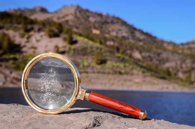 Foto onderzoeksconcept magnify glass loupe op de vulkanische rots bij een meer