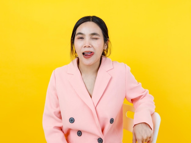 Ondeugend en sexy Aziatisch meisje op een mooi roze jasje draait de tong, sluit het oog en poseert een grapje voor de lol en allure. Aantrekkelijk vrouwenmodel voor leuke moderne uitrustingsmode van jonge vrouwelijke levensstijl.