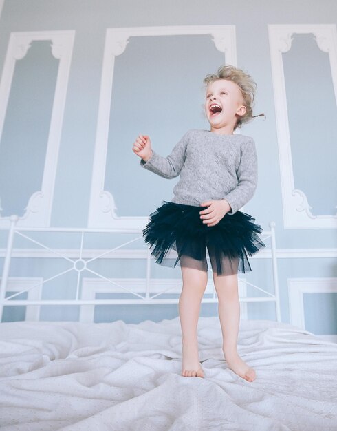 Ondeugend klein meisje dat op het bed van de ouders springt