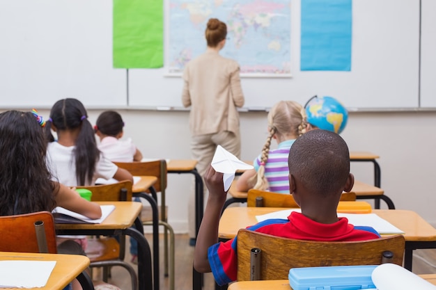 Ondeugende leerling op het punt om papieren vliegtuigje in de klas te gooien