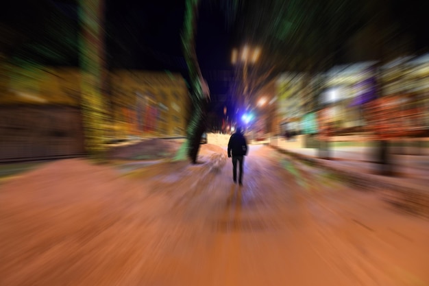 Foto onduidelijk beeld van een man die's nachts op een met sneeuw bedekte voetpad loopt