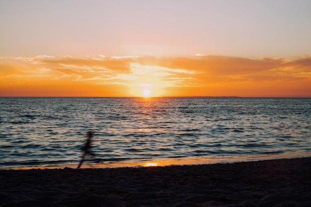 Onduidelijke beweging van een kind dat tijdens de zonsondergang op het strand tegen de lucht loopt