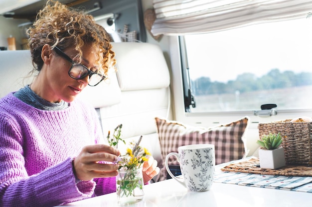 キャンピングカーの中の植物と花を世話する1人の大人の女性 現代的な小さな家 モーターホームRV 一人で バンライフをフルタイムで生きる人々 人と自然 幸せな若い成熟した女性 屋内レジャー