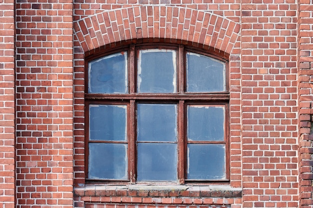 One arched glass window on old red brick wall