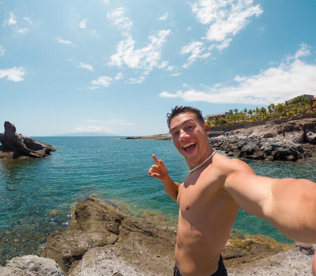 One attractive and happy young man at the beach smiling and looking at the camera