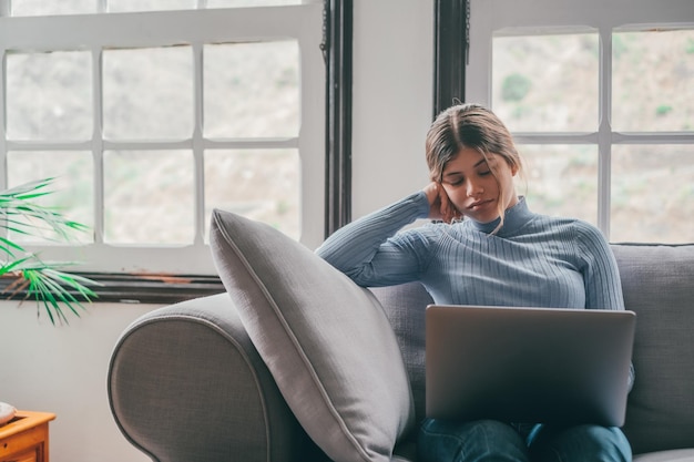 Una bella adolescente che dorme e si riposa sul divano mentre studia o lavora a casa millennial si prende una pausa dopo aver fatto i compiti usando il laptop